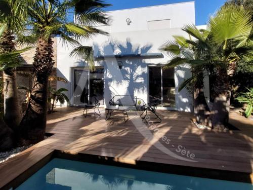une maison avec une piscine et des palmiers dans l'établissement Super villa 6 personnes avec piscine et climatisation a cote des plages, à Sète