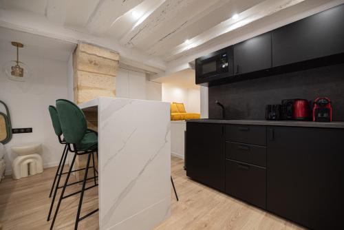 une cuisine avec des armoires noires et un fauteuil vert dans l'établissement CIA - Studio in Heart of Le Marais 4P, à Paris