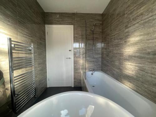 a bathroom with a bath tub and a shower at Spacious and Modern Home in Woodhouse - Sleeps 10 in Central Station
