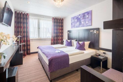 una camera d'albergo con un grande letto con lenzuola viola di Best Western City Hotel Pirmasens a Pirmasens