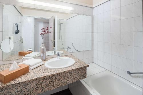 a bathroom with a sink and a tub and a mirror at Best Western Hotel Mainz in Mainz