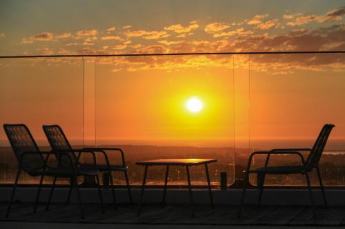 a sunset on a roof with chairs and a table at Monte Sardinha in Santiago do Cacém