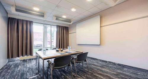 a meeting room with a table and chairs and a whiteboard at Best Western Hotel Heidehof in Hermannsburg