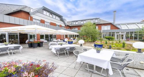 a patio with white tables and chairs in front of a building at Best Western Hotel Heidehof in Hermannsburg