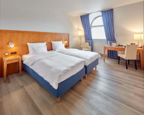 a bedroom with a large bed and a desk at Best Western Hotel Trier City in Trier