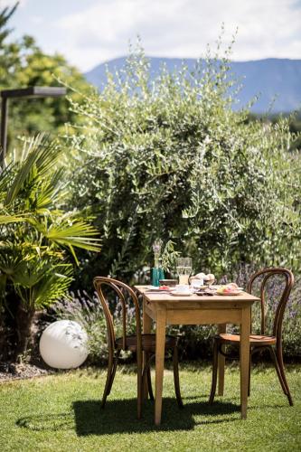 a wooden table and two chairs in the grass at Romantik Hotel Jagdhof in Caldaro