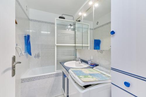 une salle de bain blanche avec un lavabo et une baignoire dans l'établissement Le 32 de Cabourg - A 400 m de la plage, à Cabourg