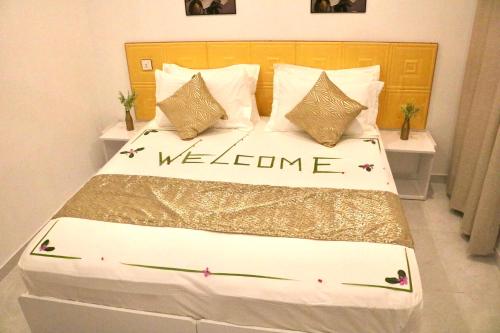 a bedroom with a bed with a welcome sign on it at Sea Sun Stay in Maafushi