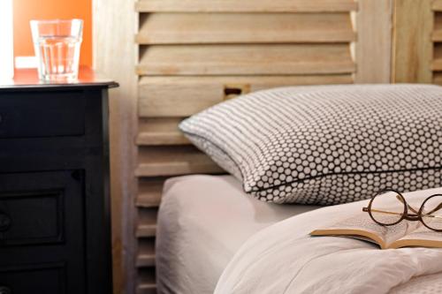 une paire de lunettes assise sur un lit avec un livre dans l'établissement Les bergeries alivaccia, à Figari