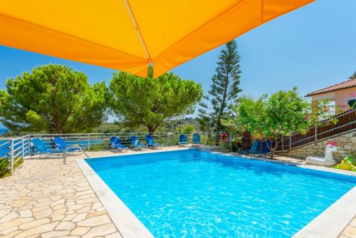 a swimming pool with an orange umbrella and chairs at Dolphin studio in Gaios