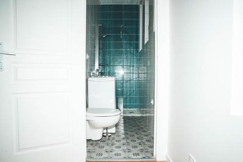 La salle de bains est pourvue de toilettes et de murs carrelés verts. dans l'établissement Hostel Bords de Marne 3, à Gournay-sur-Marne