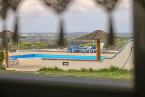 a swimming pool with a table and a umbrella at Monte Sardinha in Santiago do Cacém