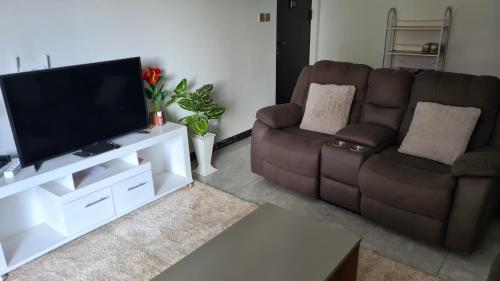 a living room with a flat screen tv and two chairs at Diamond in Kileleshwa Othaya Rd in Nairobi