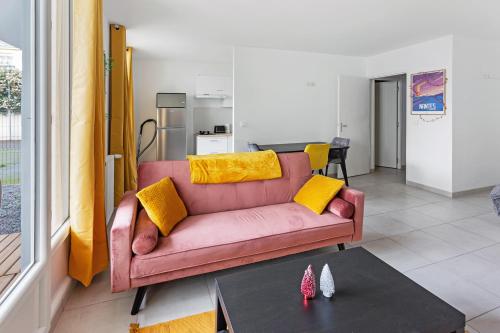 un salon avec un canapé rose et une table dans l'établissement Le Petit Patio - Rénové, paisible et proche centre, à Nantes