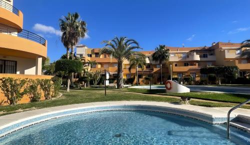 ein Swimmingpool vor einem Gebäude mit Palmen in der Unterkunft Indalia Natura, apartamento nudista en Vera playa in Vera
