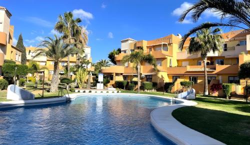 einen Pool in einem Resort mit Palmen und Gebäuden in der Unterkunft Indalia Natura, apartamento nudista en Vera playa in Vera