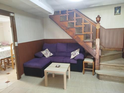 a living room with a purple couch and a staircase at El Pedrosu casa para 6 personas en Espinareu in Cuerrías