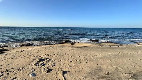 a beach with footprints in the sand and the ocean at Appartamento Quadrifoglio in Castelsardo