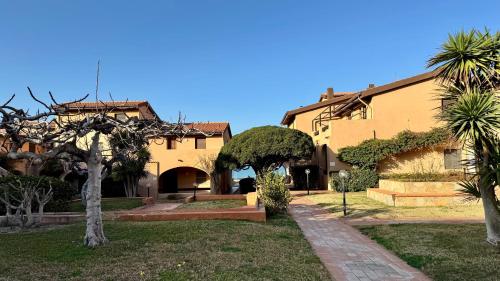 a large yellow building with trees in a yard at Appartamento Quadrifoglio in Castelsardo