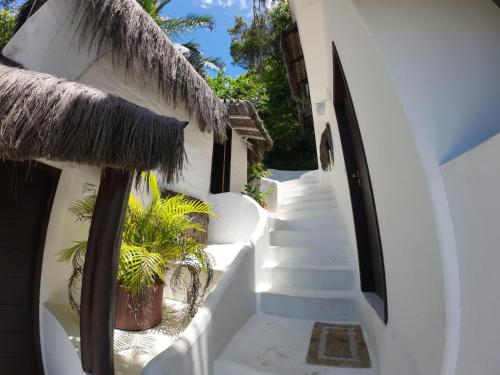 a stairway leading to a building with a straw roof at Pousada Ponta Das Pedras in Morro de São Paulo