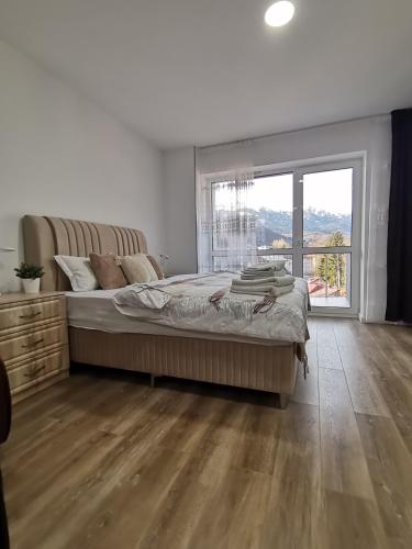 a bedroom with a large bed and a large window at Tutu Studio Sinaia cu vedere panoramica Early Checkin in Sinaia