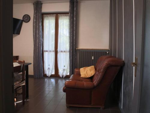 a living room with a brown leather chair and a clock at Casa Migliardi Colors in Nizza Monferrato