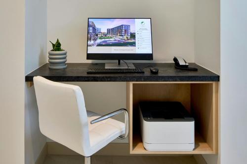 a desk with a computer monitor and a white chair at Element Atlanta Perimeter Center in Atlanta