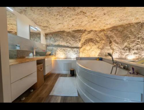 La salle de bains est pourvue d'une baignoire et d'un mur en pierre. dans l'établissement Maison troglodyte, à Poitiers