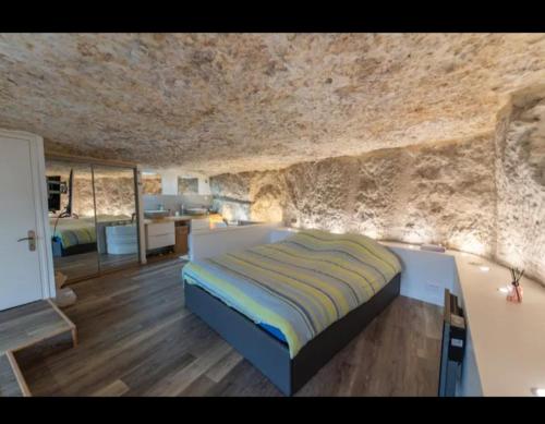 une chambre avec un lit et un mur en pierre dans l'établissement Maison troglodyte, à Poitiers