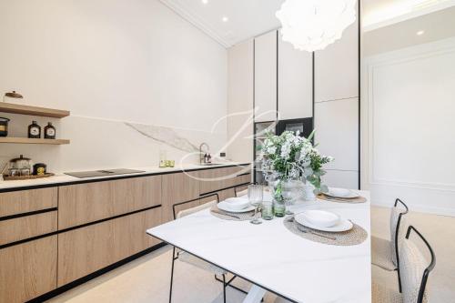 une cuisine blanche avec une table et des chaises dans l'établissement Le Mané - Haussmannien Centre Cannes accommodation, à Cannes