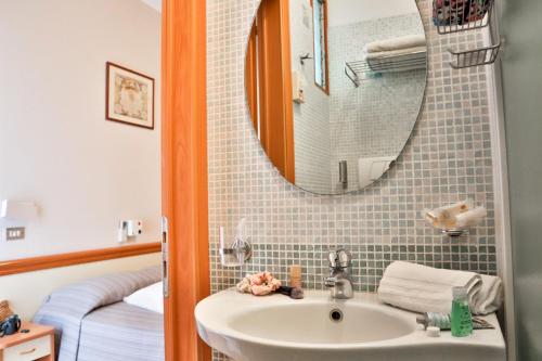 a bathroom with a sink and a mirror and a bed at Hotel Nevada in Bellaria-Igea Marina