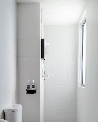 a white bathroom with a shower and a toilet at Relaxing 3BR Family Home near Zoo with Netflix WiFi in Tupai