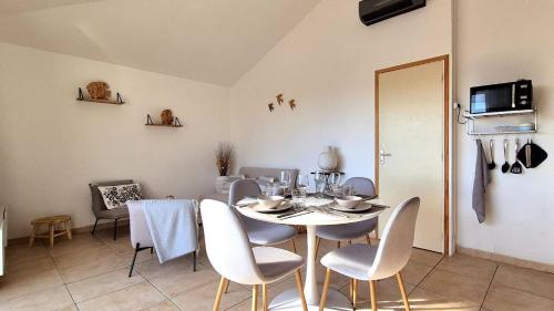 une salle à manger avec une table et des chaises blanches dans l'établissement Appartement Ruscana, 4 pers, 90 m plage, à Pinarellu