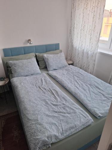 two beds in a bedroom with blue sheets and pillows at Apartman u Zemunu in Zemun
