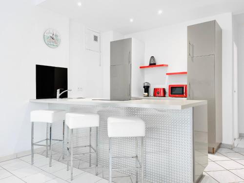 une cuisine avec un comptoir blanc et des tabourets de bar dans l'établissement Le Germain - Logement 3 pièces, à Cannes