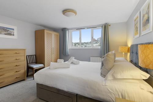 a bedroom with a large white bed and a chair at High Hopes, Harbour Location with Sea Views in Brixham
