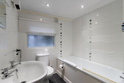 a white bathroom with a sink and a tub and a toilet at High Hopes, Harbour Location with Sea Views in Brixham