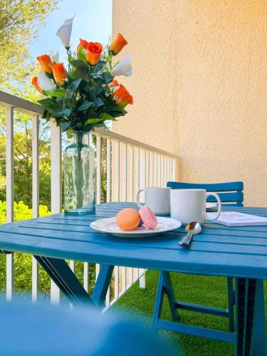 une table bleue avec un vase de fleurs et une assiette de nourriture dans l'établissement T2 - accès plage - balcon et parking privé, à Sanary-sur-Mer