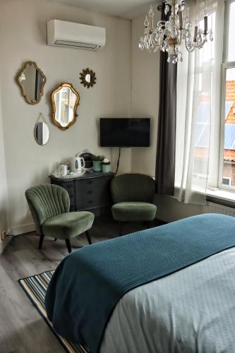 a bedroom with a bed and a chair and a mirror at B&B Zeeuws genoegen in Vlissingen