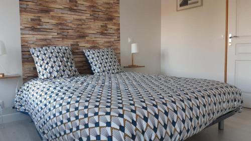 une chambre avec un grand lit avec un mur de briques dans l'établissement Le BOTELLA, à Teurthéville-Hague