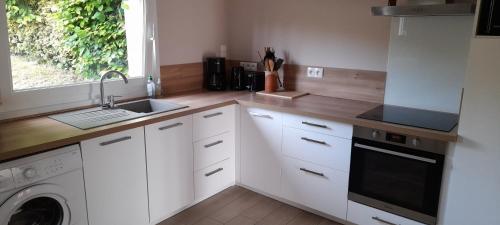 une cuisine blanche avec un évier et un lave-vaisselle dans l'établissement Le BOTELLA, à Teurthéville-Hague