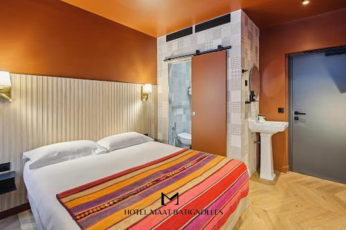 une chambre avec un grand lit et une salle de bain dans l'établissement Hôtel Maât Batignolles, à Paris