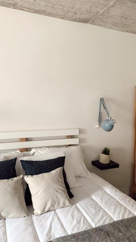 a white bed with white pillows and a lamp at Láurea Ecocasona in Oreña