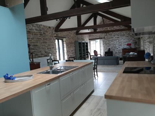 une cuisine avec des placards blancs et un mur en briques dans l'établissement La Sellerie, à Concarneau