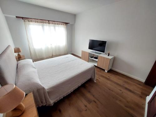 a white bedroom with a bed and a television at Retoño Serrano in Tandil
