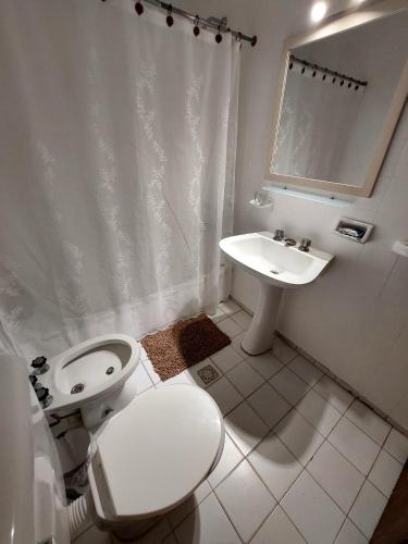 a white bathroom with a toilet and a sink at Retoño Serrano in Tandil