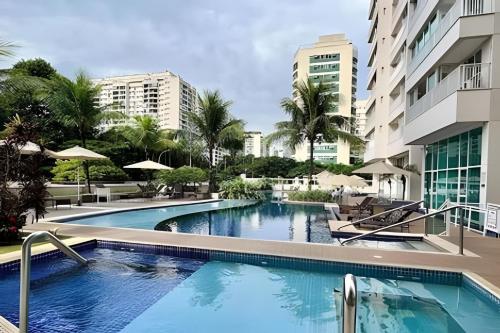 a swimming pool in a resort with palm trees and buildings at Apartamentos no Verano Stay in Rio de Janeiro