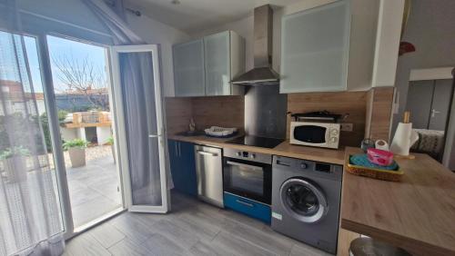 une cuisine avec un lave-linge et un micro-ondes dans l'établissement Villa Verger - Maison de plain pied - 2 chambres - clim - 2 grandes terrasses - proche plage et commerces, à Saint Cyprien Plage