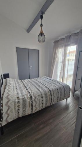 un lit dans une chambre avec une grande fenêtre dans l'établissement Villa Verger - Maison de plain pied - 2 chambres - clim - 2 grandes terrasses - proche plage et commerces, à Saint Cyprien Plage