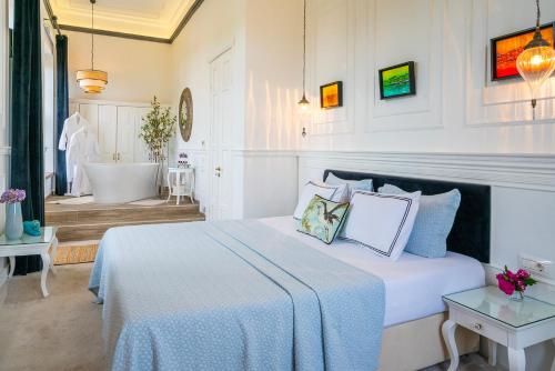 a white bedroom with a bed and a bath tub at Siyah Lale Cunda 1841 in Cunda